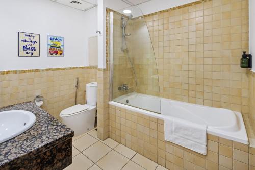a bathroom with a tub and a toilet and a sink at La Buena Vida Holiday Homes - Modern, Luxe & Spacious 4-Bed, Full Kitchen, near to Beach, Tram & Marina in Dubai