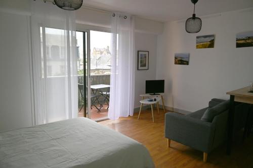 - une chambre avec un lit, une chaise et un balcon dans l'établissement Studio Le Saint Paul, Granville, à Granville