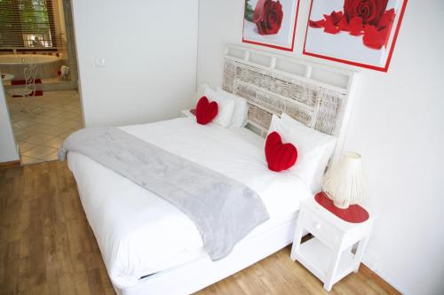 a bedroom with a white bed with red pillows at FM GUEST LODGE Comfort, Tranquility & Peace of Mind in Johannesburg