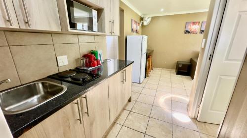 a kitchen with a sink and a refrigerator at FM GUEST LODGE Comfort, Tranquility & Peace of Mind in Johannesburg