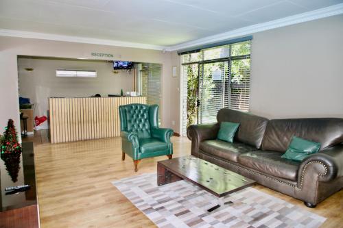 a living room with a leather couch and a chair at FM GUEST LODGE Comfort, Tranquility & Peace of Mind in Johannesburg