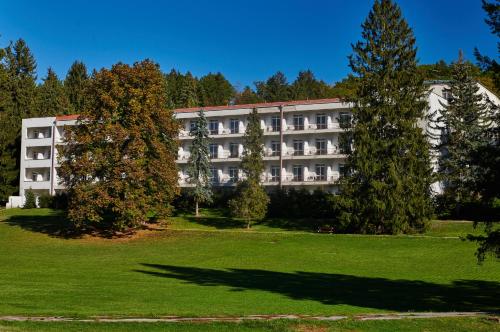 an apartment building with trees in front of a park at Hotel Palace - KÚPELE SLIAČ in Sliač