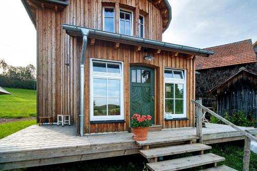 a wooden house with a green door and a porch at Uptrulli-Minihaus in Vogt