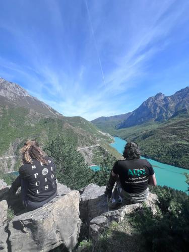two people sitting on a rock looking at a river at Lulebore Guesthouse in Lekbibaj