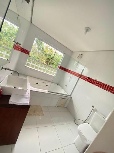 a bathroom with a toilet and a sink and a window at Refúgio das Ondas I Suítes perto da praia com conforto e self check-in in Bertioga