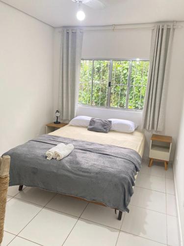 a bedroom with a large bed with a window at Refúgio das Ondas I Suítes perto da praia com conforto e self check-in in Bertioga