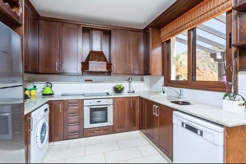 a kitchen with wooden cabinets and white appliances at Mermaid Villa in Pomos
