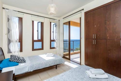 a bedroom with a bed and a balcony with the ocean at Mermaid Villa in Pomos