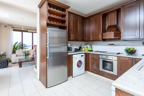 a kitchen with wooden cabinets and a stainless steel refrigerator at Mermaid Villa in Pomos