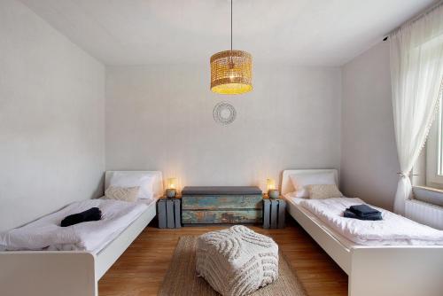 two beds in a white room with a chandelier at sennefeeling in Hövelhof