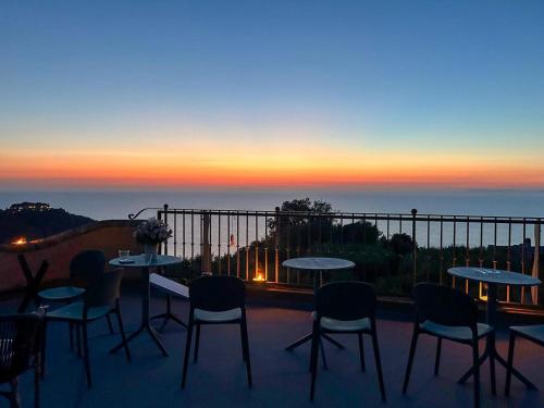 a group of tables and chairs on a balcony with a sunset at Villa Velta Sea Sunset in Porto Santo Stefano