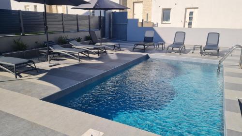 a swimming pool with chairs and an umbrella on a building at VAL22,VILLA 200 m from BEACH WITH POOL AND FITNESS in Funtana