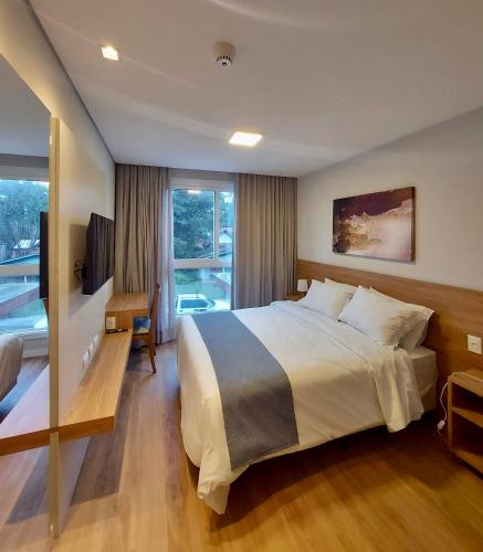a bedroom with a large bed and a balcony at Lindo Flat no Serra Class com Piscina e Sauna in Canela