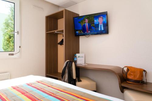 a hospital room with a bed and a tv on the wall at Brit Hotel Le Kerann Nantes St Herblain - Zac De La Lorie in Saint-Herblain