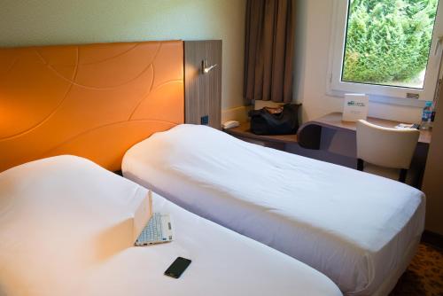 a hotel room with two beds and a desk at Brit Hotel Le Kerann Nantes St Herblain - Zac De La Lorie in Saint-Herblain