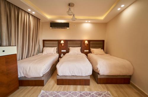 a bedroom with two beds and a tv on the wall at prestige pyramids INN in Cairo
