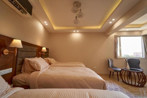 a bedroom with two beds and a table and a window at prestige pyramids INN in Cairo