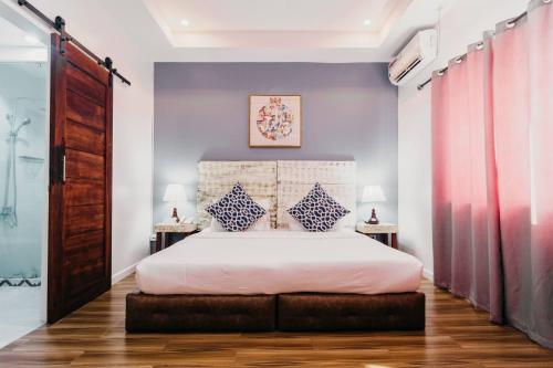 a bedroom with a white bed with two tables at The Mansion Boutique Hotel in Mabalacat