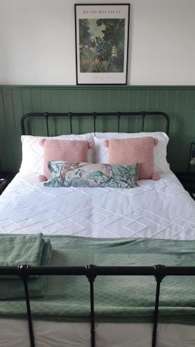 a bed with pink and white sheets and pillows at City Cottage in Lincoln