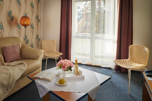 a living room with a couch and a table with flowers on it at Hotel Palace - KÚPELE SLIAČ in Sliač