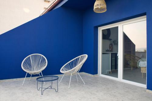 two chairs and a table in front of a blue wall at LavandinaLuxe APP in Novi Vinodolski