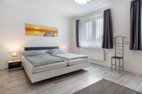 a white bedroom with a bed and two windows at Ferienhaus Heide in Bad Fallingbostel