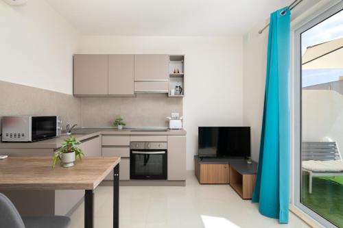 a kitchen with white cabinets and a wooden table at Sunlit Stylish Penthouse with Hot Tub - Close to Sliema Promenade, St Julian's & St Georges Bay in Il-Gżira