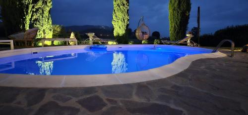 a large swimming pool with blue water at night at Il Casale La Duchessa in Vetulonia