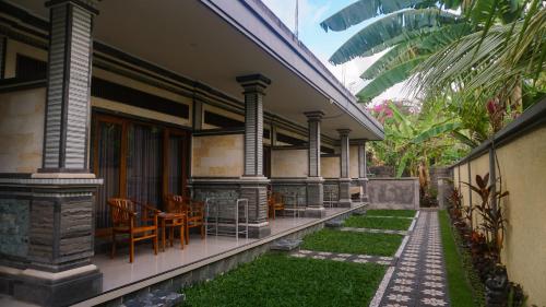 a porch of a house with chairs and a table at Nick Homestay Bali in Uluwatu
