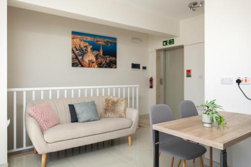 a living room with a couch and a table at Sunlit Stylish Penthouse with Hot Tub - Close to Sliema Promenade, St Julian's & St Georges Bay in Il-Gżira