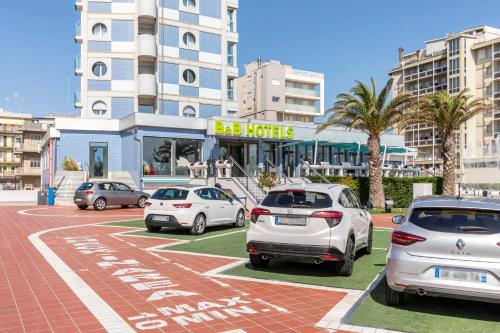 a parking lot with cars parked in front of a hotel at B&B Hotel Chioggia Airone in Sottomarina