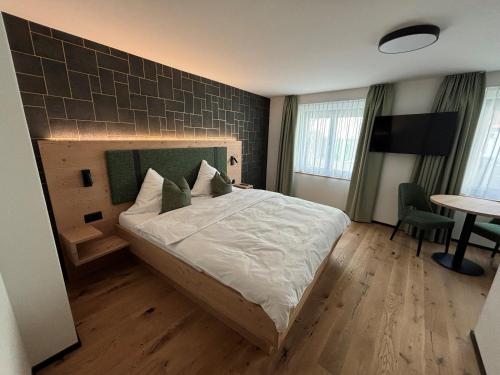 a bedroom with a bed and a desk and a table at Appart Hotel Pitschonia Self Check-In in Andeer