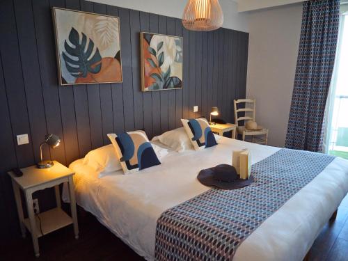a bedroom with a large bed with a hat on it at Hôtel de La Marée - Face à l'océan - Ile de Ré in Rivedoux-Plage