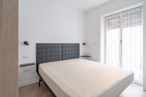 a white bedroom with a large bed and a window at E&J Mare e Relax in Sanremo