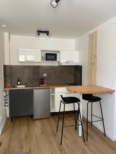 La cuisine est équipée d'une table, d'un évier et d'un four micro-ondes. dans l'établissement Appartement T2 meublé 2ter, à Saint-Symphorien-dʼOzon
