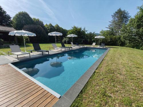 une piscine avec chaises et parasols dans une cour dans l'établissement Château du Chambon, à Cerzat