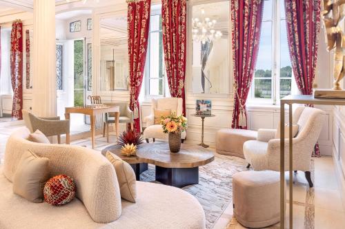 a living room with red curtains and a table and chairs at La Nauve, Hôtel & Jardin - Relais & Châteaux in Cognac