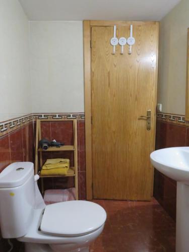 Un baño con inodoro y puerta de madera. en Casa da Ponte Bragança, en Bragança