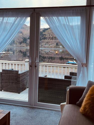 a room with a large window with a view of a lake at Lakewood Lodge in Saint Fillans
