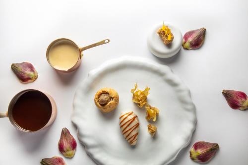 a white plate with donuts and a cup of coffee at La Nauve, Hôtel & Jardin - Relais & Châteaux in Cognac