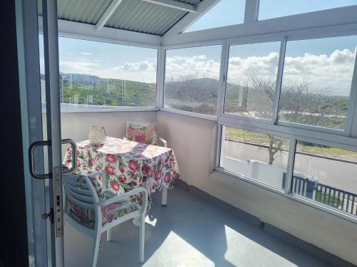 a table and chairs in a room with windows at Studio on Atlantic in Yzerfontein