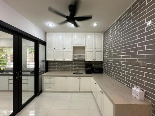 a kitchen with white cabinets and a ceiling fan at Landed House Gelugor 5BR 3B-20pax by 3C in Gelugor