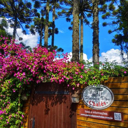 a sign on a fence with pink flowers at Chalé Temático em Pipa de Vinho - Parada da Pipa Chalés in Canela