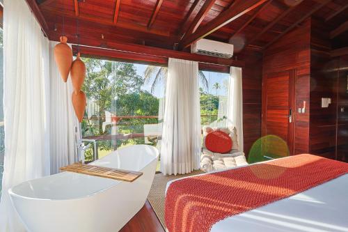 a bedroom with a tub and a large window at Eco Luar Boutique Hotel in Igarassu