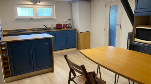 une cuisine avec des placards bleus et une table en bois dans l'établissement 2 pièces de plain-pied avec parking et jardin au calme, à Antony