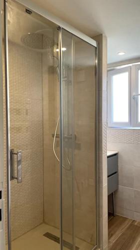 une douche avec une porte vitrée dans une salle de bain dans l'établissement Maison Calme & Jardin au Bouscat, à Le Bouscat