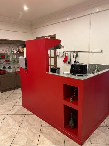 - une cuisine avec comptoir rouge dans une pièce dans l'établissement Côté Boulevard, à Bastia
