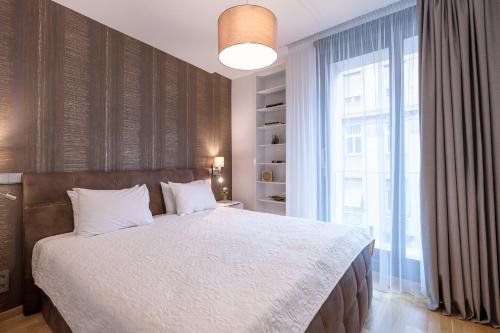 a bedroom with a large bed and a large window at Emerald Downtown Luxury Suites by Continental Group in Budapest