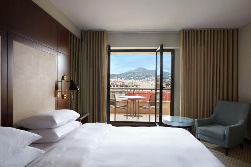 a hotel room with a bed and a chair and a balcony at Hyatt Regency Nice Palais de la Méditerranée in Nice