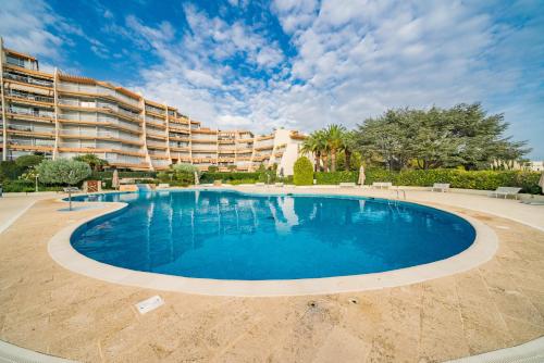 une grande piscine en face d'un grand bâtiment dans l'établissement Studio Cannes Marina Jean Bart, à Mandelieu-la-Napoule